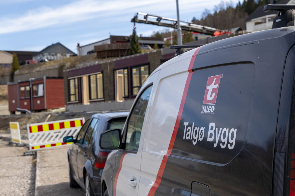 Talgø Bygg servicebil på byggeplass der håndverkere jobber med oppføring av bolig.